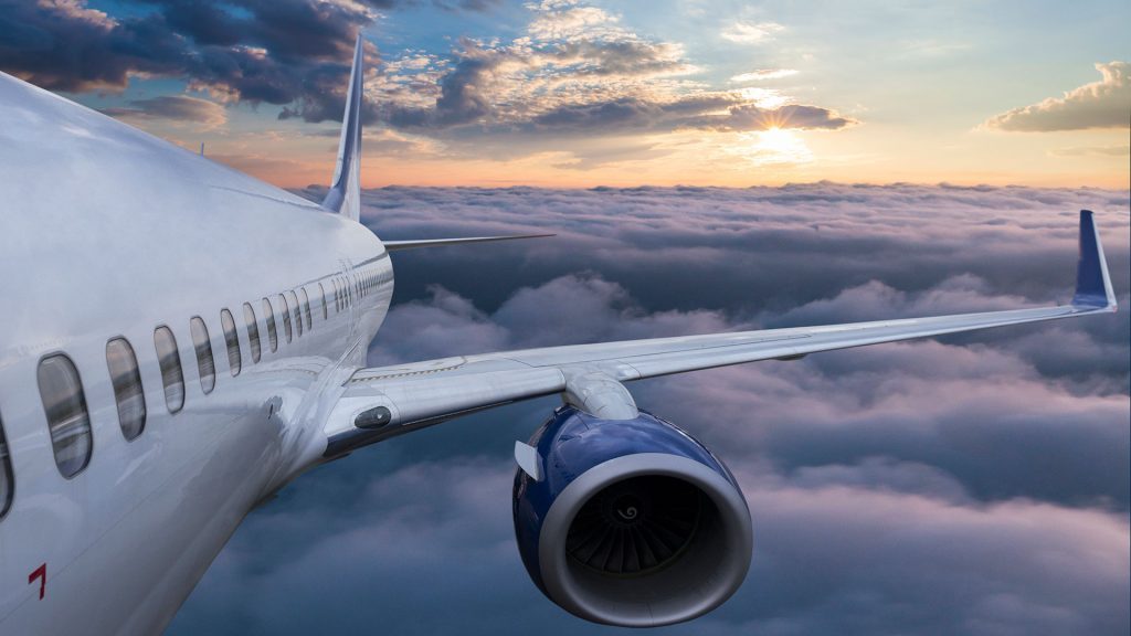 Avión blanco volando en un atardecer por arriba de las nubes