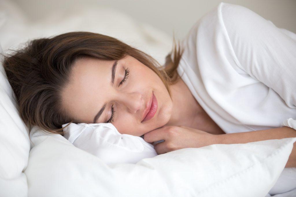 Mujer acostada en su cama teniendo un buen ciclo de sueño.