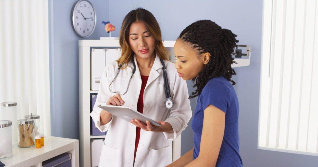 Doctora atendiendo una mujer y enseñándole algo en su tablet. 