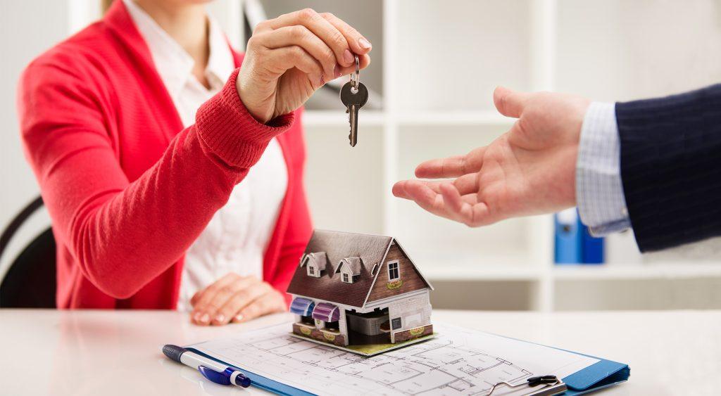 Una señora con una llave en la mano dándosela a otra persona representando la compra de una casa